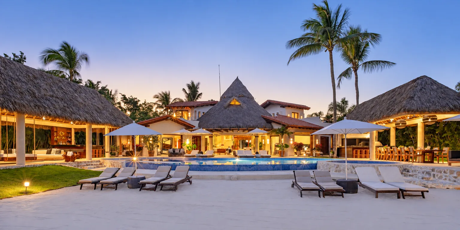 An illuminated tropical villa and pool at dusk