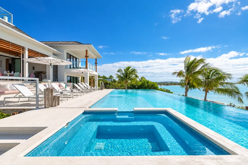 Sunlit private villa beside a turquoise infinity pool